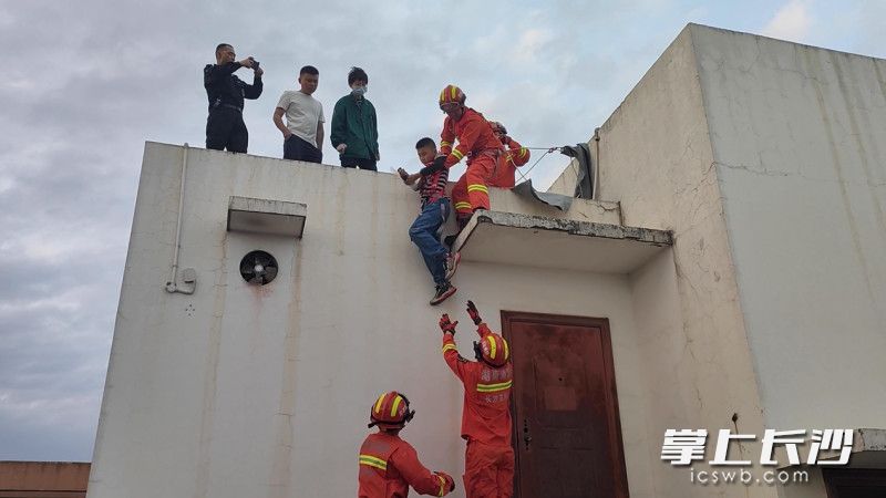 救援现场，消防救援人员小心翼翼将孩子从楼顶救下。长沙晚报通讯员 张佳欣 供图