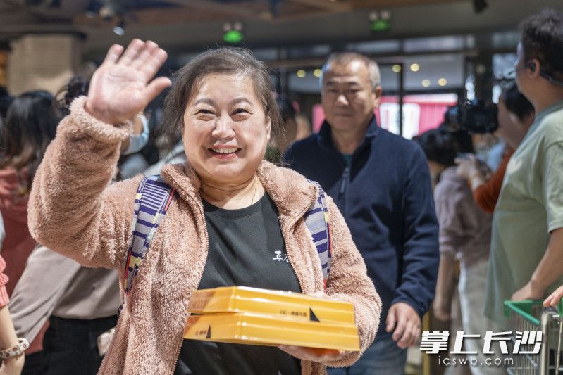 市民购买到了胖东来网红“大月饼”，开心地向镜头招手。
