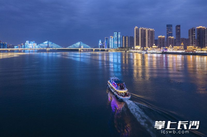 入夜，挂满彩灯的游轮与五彩霓虹的湘江两岸交相辉映。
