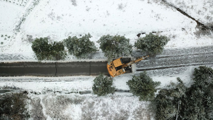 2月5日，挖掘机在湖南省临湘市坦渡镇清理路面积雪与倒伏树枝（无人机照片）。新华社记者陈振海摄